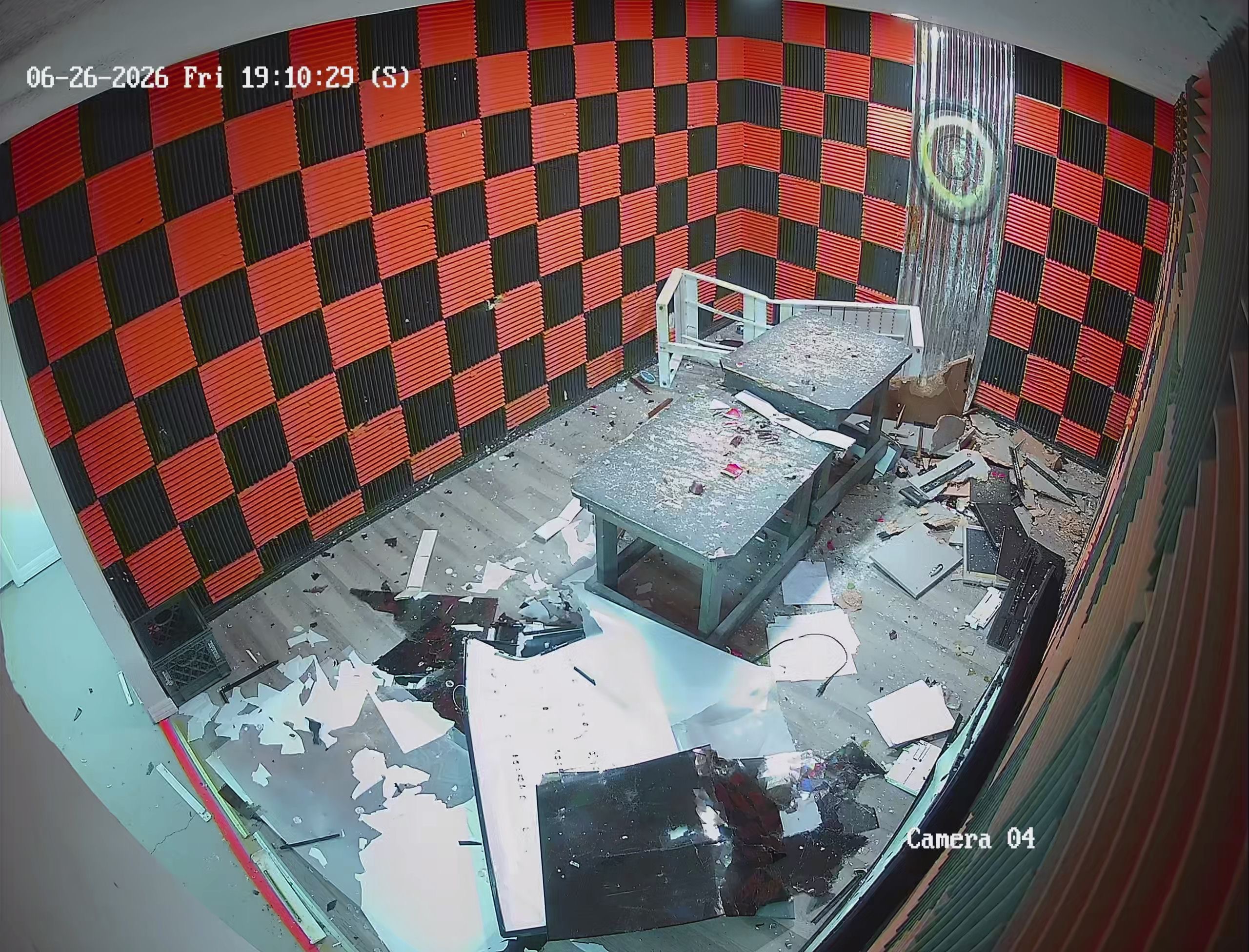 Security camera view of Crash Out rage room aftermath — floor covered in shattered electronics and debris